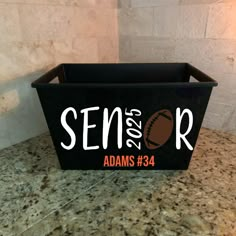 a black box with the word senior and an image of a baseball in it on a granite countertop