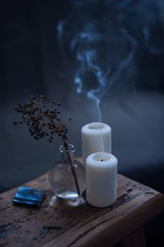 two white candles sitting on top of a wooden table