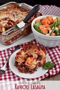 a casserole dish with meat, cheese and vegetables on a table next to a bowl of salad