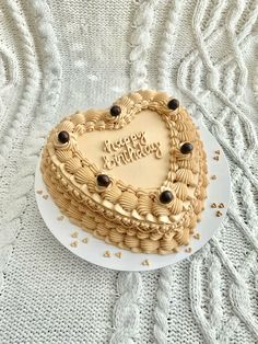 a heart shaped cake on a plate with the words happy birthday written on it in gold