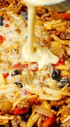 the cheese sauce is being poured on top of some pasta and other food in a skillet