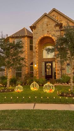 a house decorated for halloween with pumpkins in the front yard and lights on the lawn