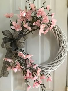 a wreath with pink flowers hanging on the front door