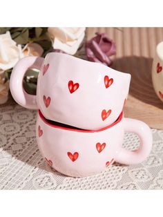 two mugs with hearts on them sitting next to each other