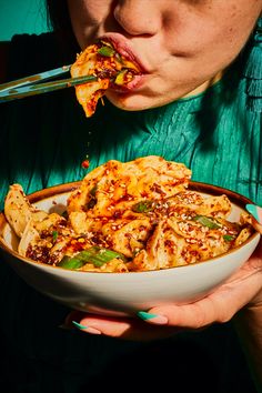 a woman is eating pasta from a bowl