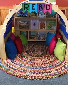 a child's reading area with bookshelves and colorful pillows on the floor