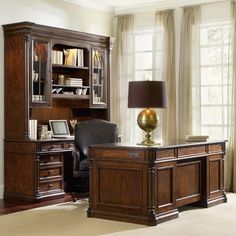 a desk with a chair, lamp and bookcase in front of a large window