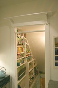 an open door to a pantry in a room with white walls and shelves filled with food