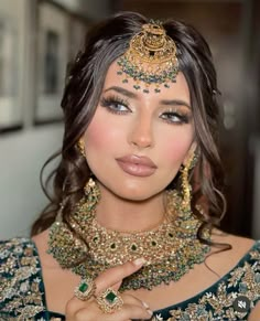 a woman in a green and gold outfit with jewelry on her head, wearing an elaborate necklace