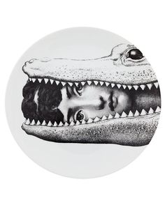 a white plate with an image of two people in a crocodile's mouth on it