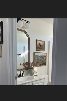 a bathroom with a sink, mirror and pictures on the wall above it's door