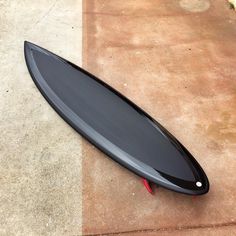 a black surfboard laying on the ground