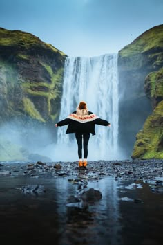 a woman standing in front of a waterfall