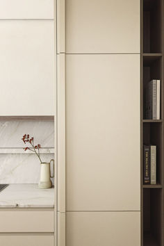 a kitchen with white cupboards and marble counter tops, along with bookshelves