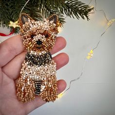 a hand holding a beaded dog ornament