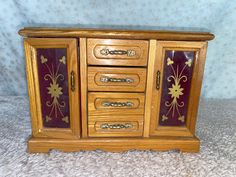 a small wooden cabinet with many drawers on it's sides and gold leaf designs painted on the doors