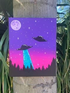 an alien painting is hanging on the side of a wooden pole in front of some trees