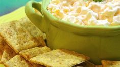 a green bowl filled with cream cheese surrounded by crackers