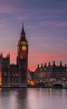 the big ben clock tower towering over the city of london at dusk, with other buildings in the background