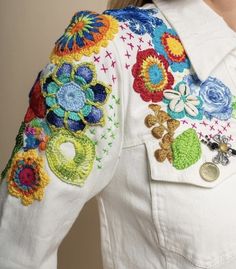 a woman wearing a white jacket with colorful flowers on it