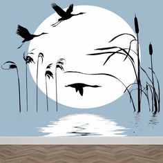 birds flying over the water in front of a full moon with reeds and grass