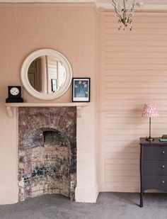 a living room with a fireplace, mirror and lamp on the wall next to it