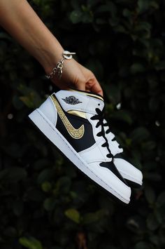 Get ready to stand out from the crowd with our eye-catching Air Jordan 1 Mid designs that blend streetwear style with luxury embellishments. Each pair in our "Bling" collection is meticulously curated to ensure you shine bright wherever you go. Note: Please be aware that these Nike sneakers are available in Girls Grade School Sizes 3.5-7, which can accommodate up to a women's size 8.5. To find your corresponding size in Girls, simply subtract 1.5 from your usual women's size. For instance, if you typically wear a Women's 7, your size in Girls would be 5.5. Handcrafted custom made-to-order sneaker. Adorned with rhinestones/crystals (all 4 swooshes) Brand new 100% authentic Air Jordan 1 Mid with box! Free shipping within the US territory! Gold Jordans, Black And Gold Jordans, Gold Nike Shoes, Black And White Jordans, Golden Sneakers, Air Jordan 1 Mid Gs, Custom Jordans, Painted Sneakers, Wedding Sneakers