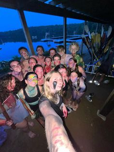 a group of people standing next to each other in front of a lake at night