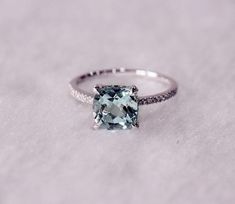 a ring with an aqua blue topazte surrounded by white diamonds on a snow covered surface