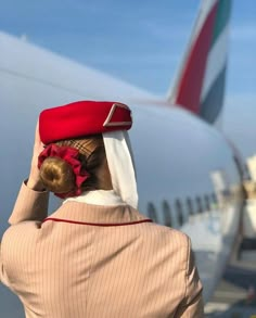 a woman wearing a red and white hat is looking at the wing of an airplane