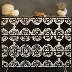 an ornate black and white cabinet with two vases on top