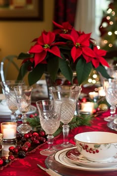 a christmas table setting with poinsettis and candles