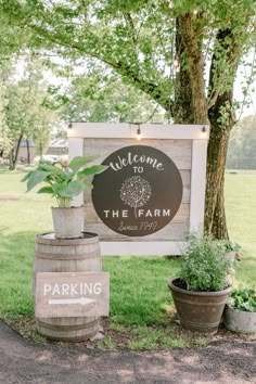 a welcome sign to the farm in front of a tree and some potted plants