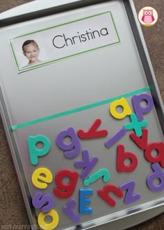 a magnetic board with magnets and letters on the bottom, in front of an image of a child's face