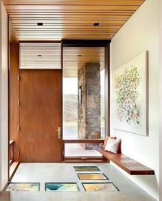 an entryway with wooden doors and artwork on the wall, along with two benches