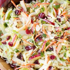 a salad with apples, cranberries, and lettuce in it on a cutting board