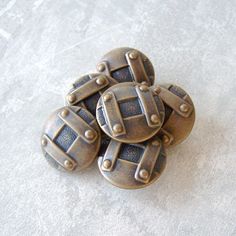 four metal buttons sitting on top of a white cloth covered floor with rivets