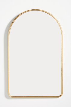 an oval mirror on a white wall with a gold border around the edge and bottom