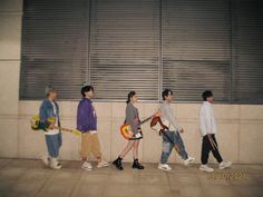 four boys walking down the street with guitars in their hands and one boy holding a guitar