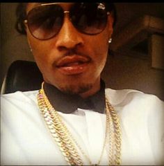 a man wearing sunglasses and a bow tie with some gold chains on his necklaces