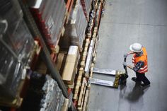 a man in an orange vest and hard hat working on a conveyor belt at a warehouse