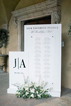 a sign that has flowers on it next to a vase with white flowers in it