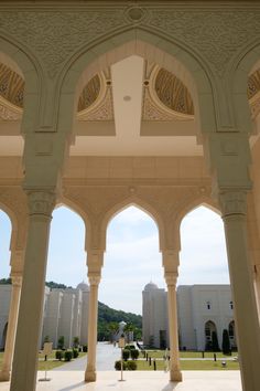 an archway in the middle of a building with columns and arches on both sides, leading into a courtyard