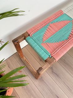 a wooden bench sitting on top of a hard wood floor next to a potted plant