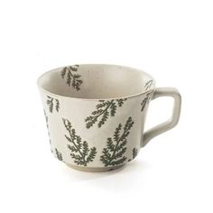 a white cup with green leaves on it