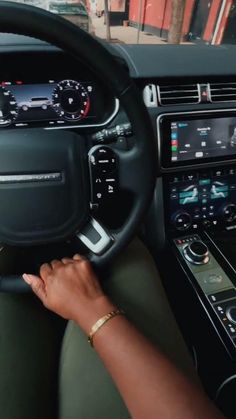 a woman driving a car with her hand on the steering wheel and dashboard controls in front of her