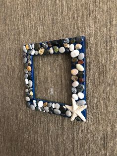 there is a blue frame made out of rocks and shells on the floor with a starfish