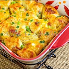 a casserole dish with green onions and cheese in it on a red plate