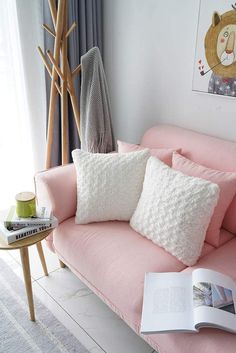 a pink couch with two pillows and a book