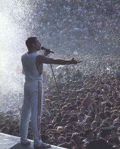 a man standing on top of a stage in front of a crowd holding a microphone